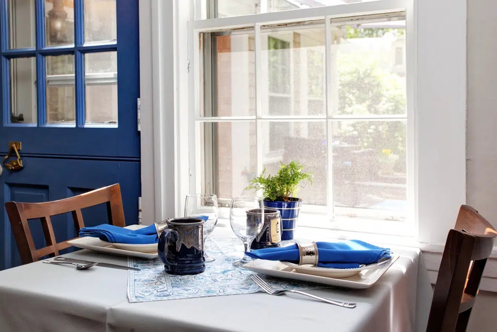 Breakfast Table for two set with white table cloth and blue linens and custom Inn Mug