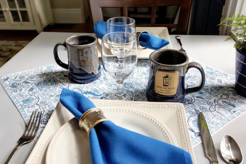 Breakfast Table for two set with white table cloth and blue linens and custom Inn Mug
