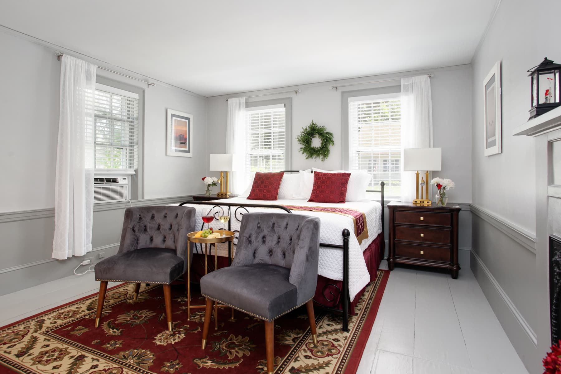 View of bedroom with bed, nightstand & lamp, two upholstered gray chairs on oriental area rug
