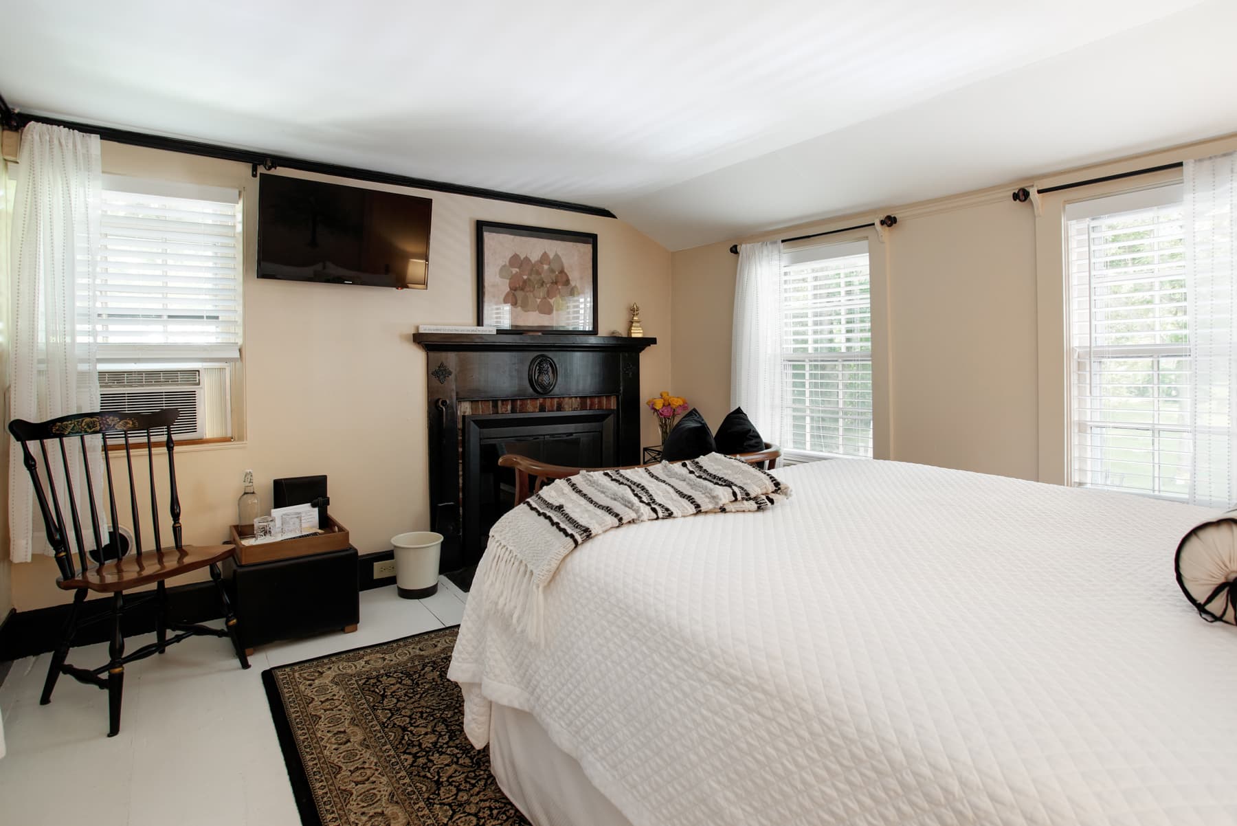 View of area opposite bed with fireplace, wall-mounted flat-screen TV, and shaker-style wooden chair