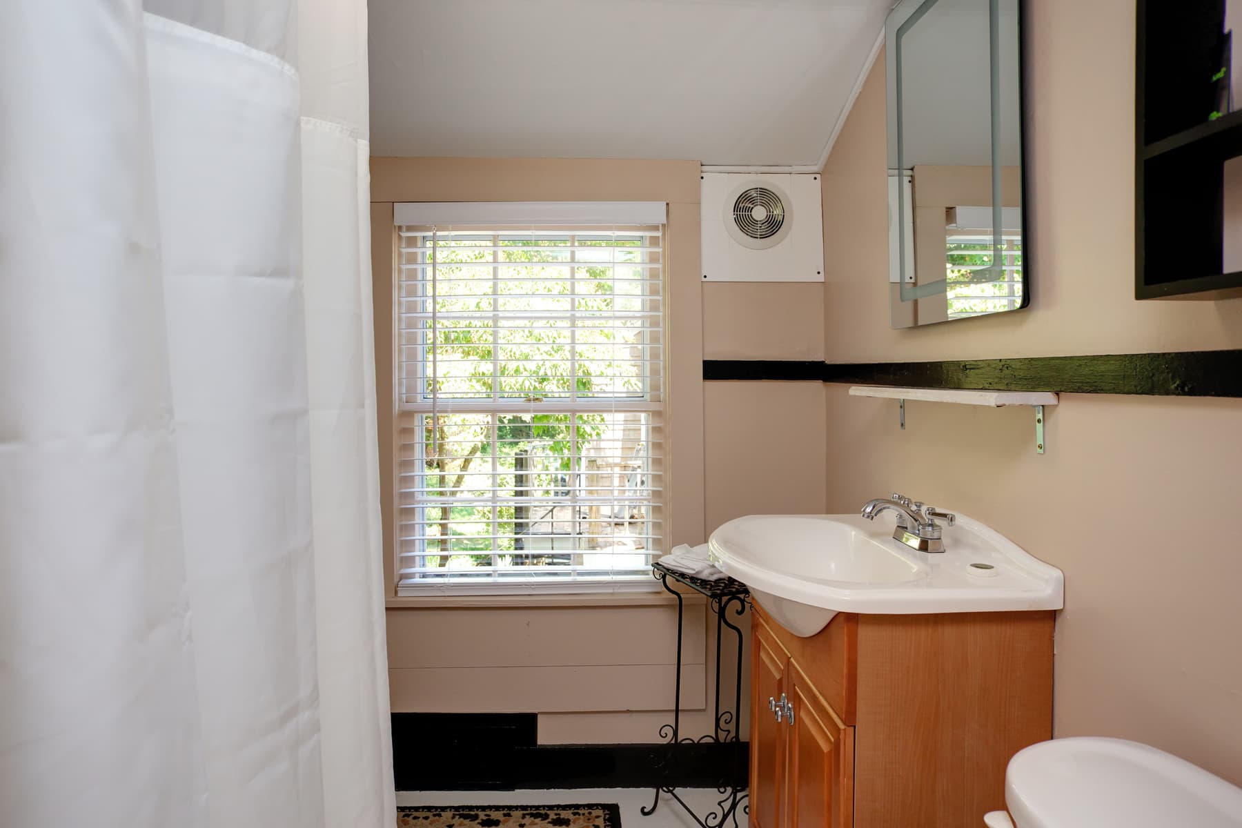 Bathroom with shower, window, vanity with sink, and toilet