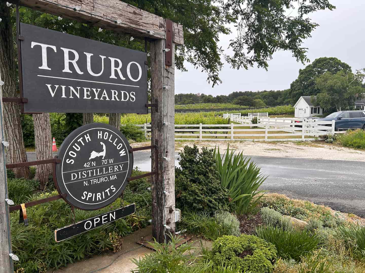 Sign for Truro Vineyards and South Hollow Distillery, with vineyards and greenery in the background.