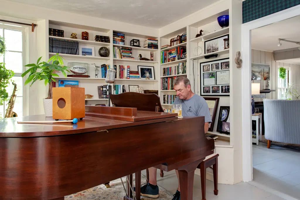 Man sitting at brown baby grand piano