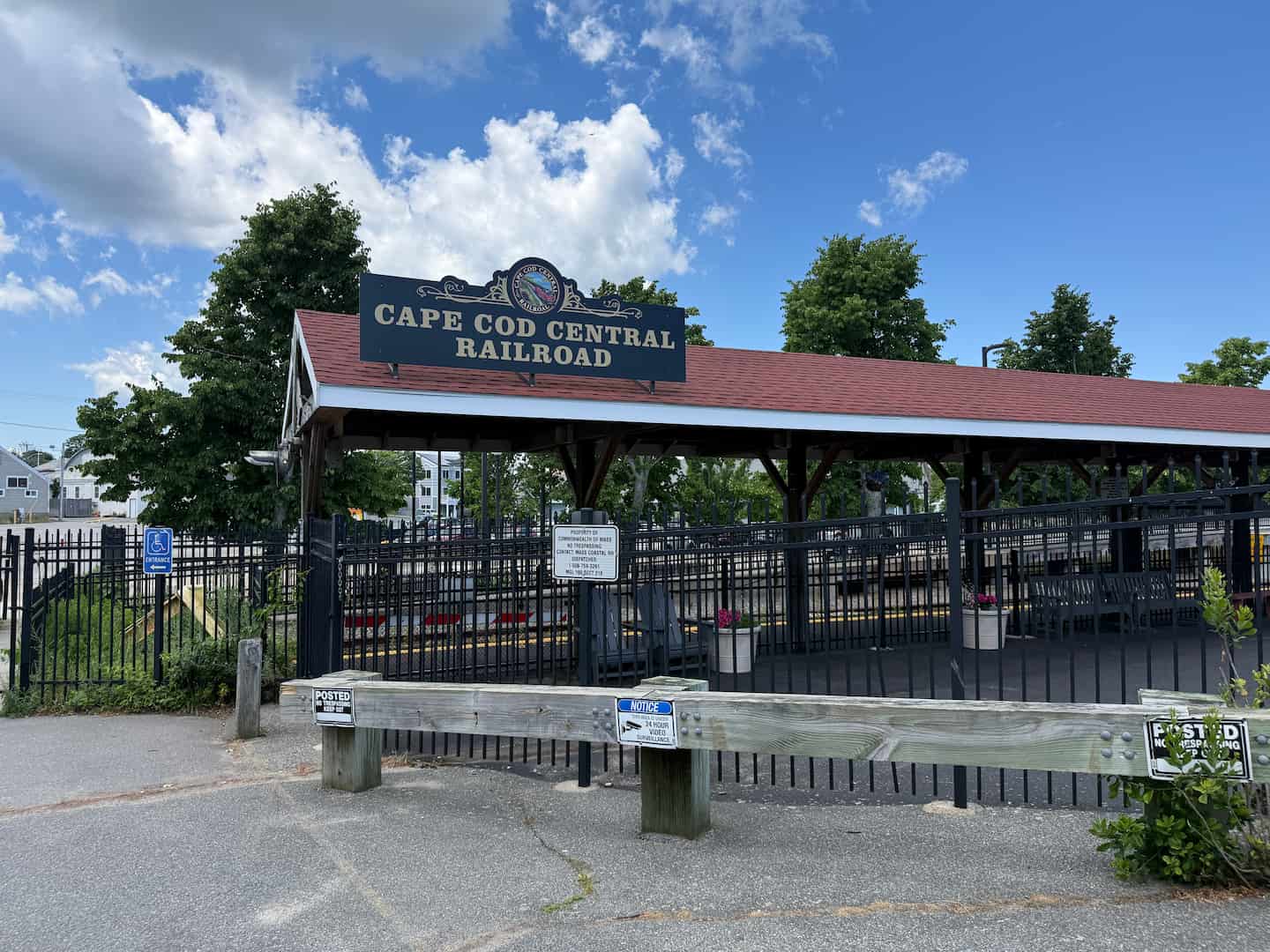 Sign for Cape Cod Central Railroad at a station with trees and blue sky in the background. Sign for Cape Cod Central Railroad at a station with trees and blue sky in the background.