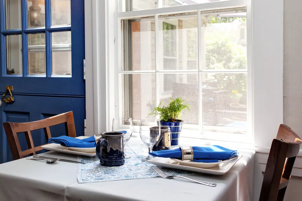 Breakfast Table for two set with white table cloth and blue linens and custom Inn Mug