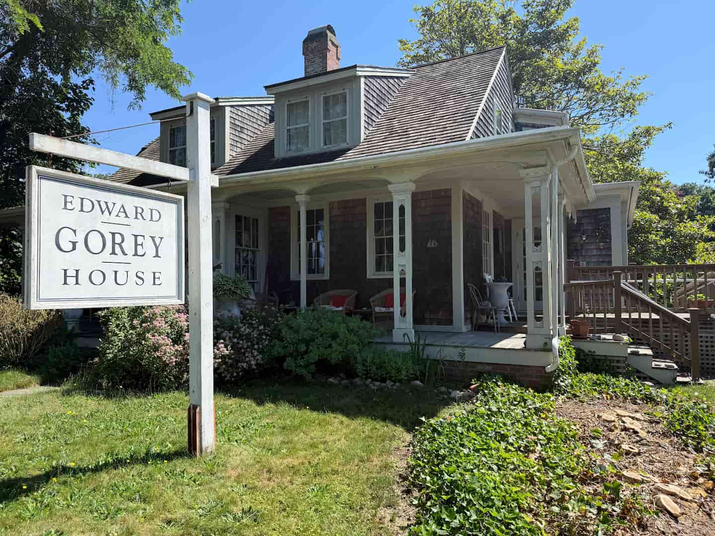 The Edward Gorey House, a quaint, shingled home surrounded by greenery. The Edward Gorey House, a quaint, shingled home surrounded by greenery.
