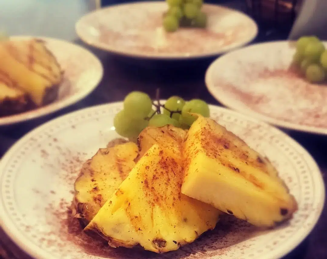 Fresh cut pineapples with cinnamon and grapes on white plates