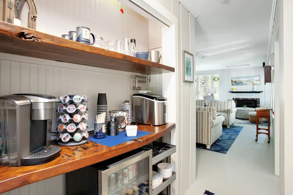 Coffee Bar and fridge, with wood counters overlooking living room with striped furniture