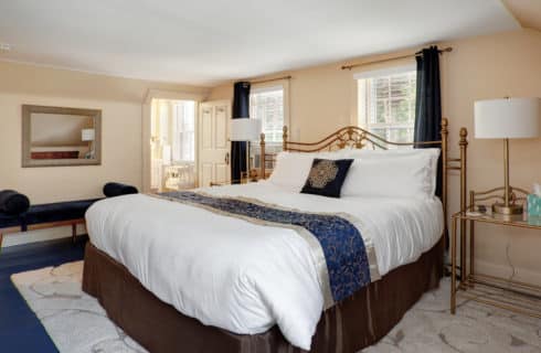 View of the Sleep number California King bed in the Nantucket guest room. End tables, lamps, wall mirror, settee, and area rug