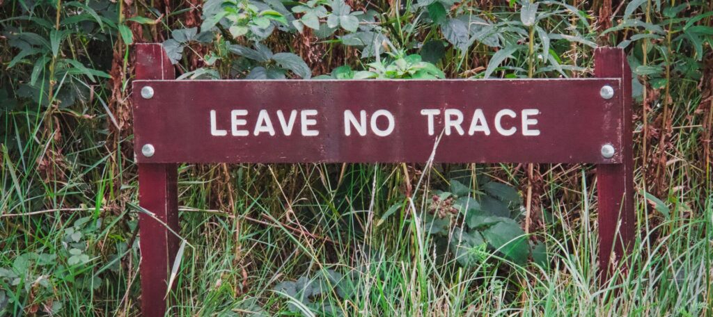 Wooden sign stating “Leave no trace” in a grassy spot